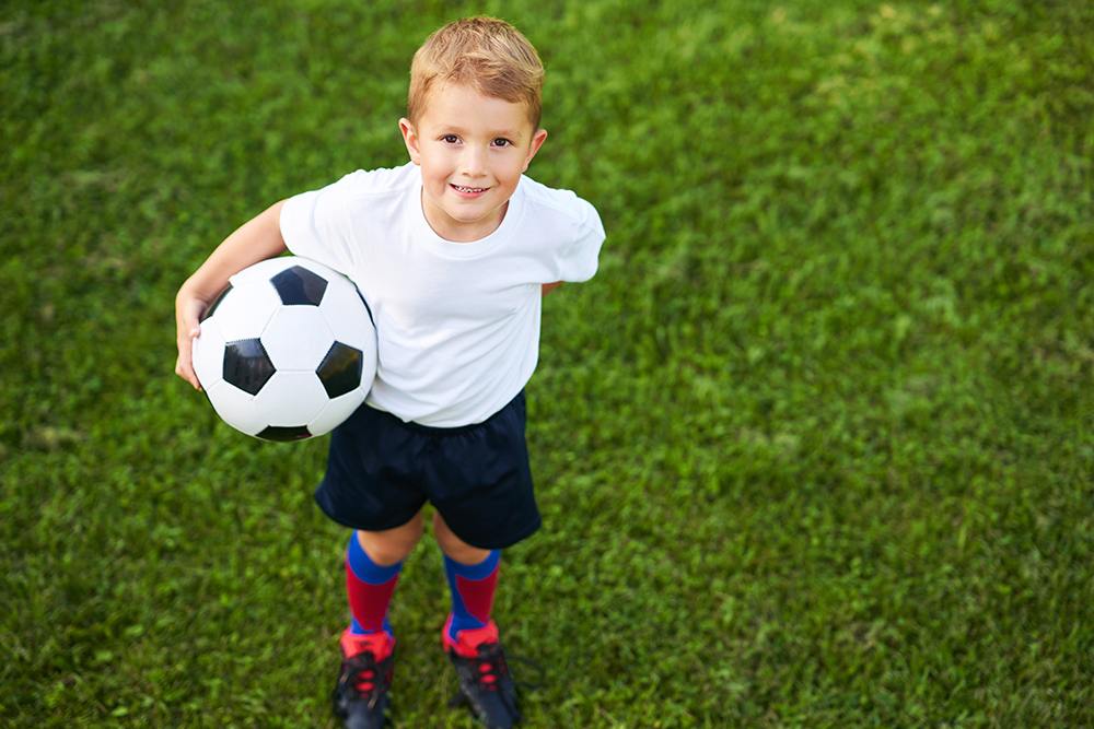 Little Boy practising football outdoors